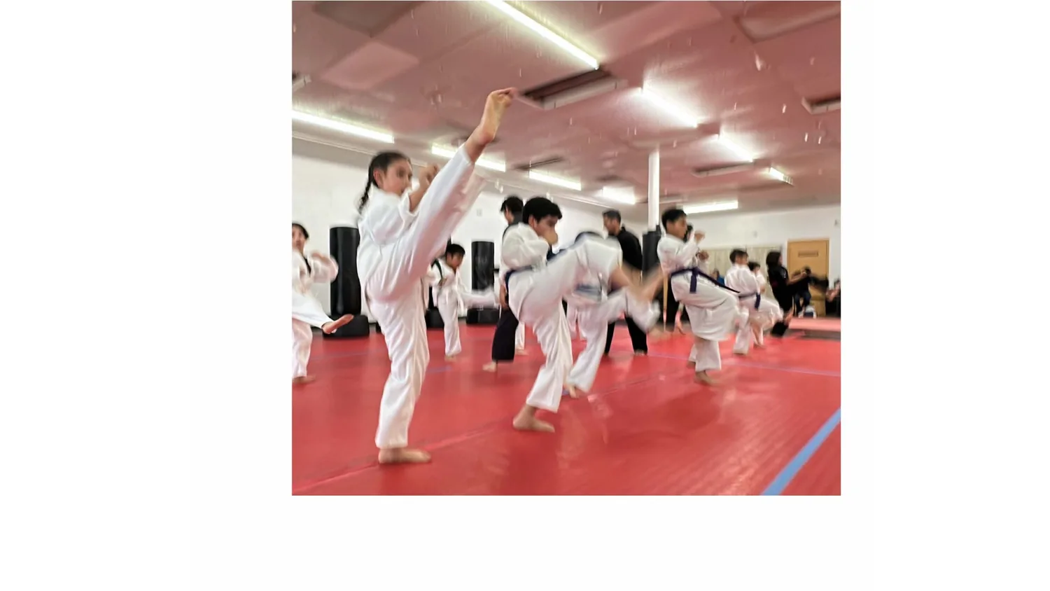 Legacy students practicing kicks together in class