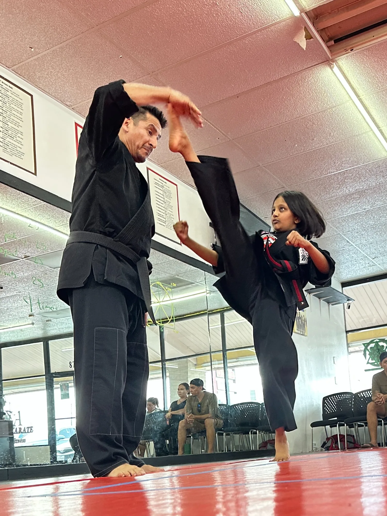 An instructor guiding a Legacy student through a high kick