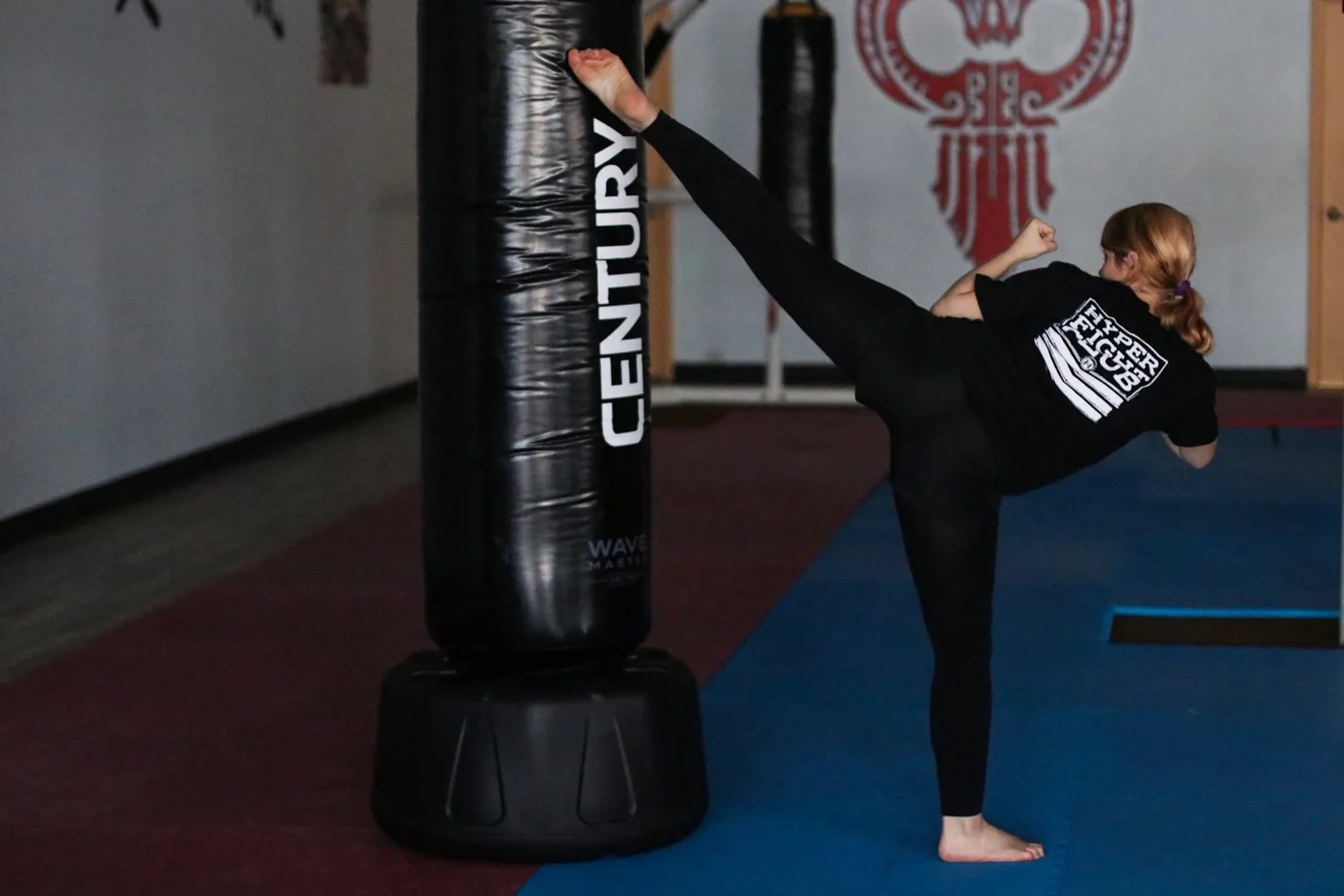 A martial artist practicing a high kick on a freestanding bag